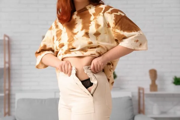 Image of woman trying to do her trousers up after pregnancy weight gain Rhyl